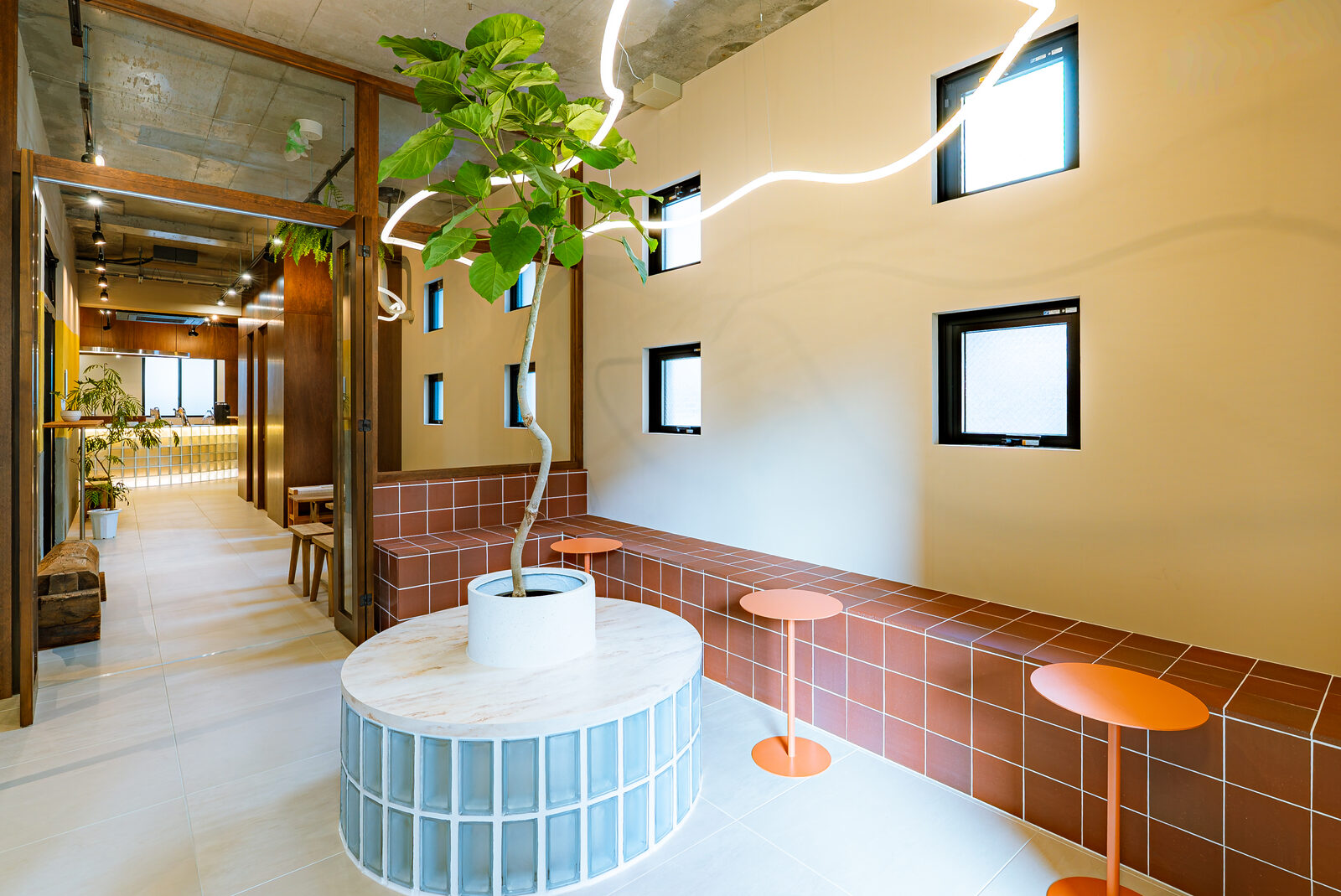 Interior of Nylon Coffee Fukuoka, with a potted tree and neon lighting above the lounge seating
