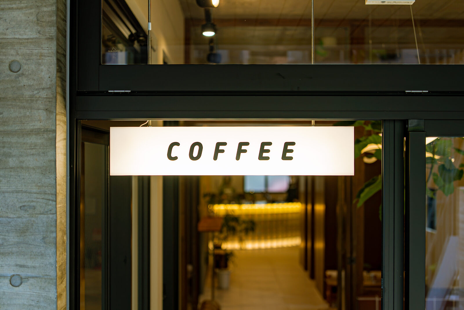 A lit COFFEE sign at the storefront